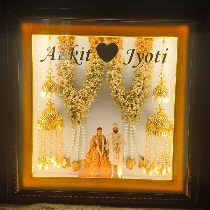 Custom handmade varmala preservation frame with couple photo, names, warm lights and preserved wedding flowers by Shaahi Decor.